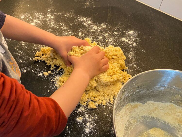 Little boy kneading the dough.