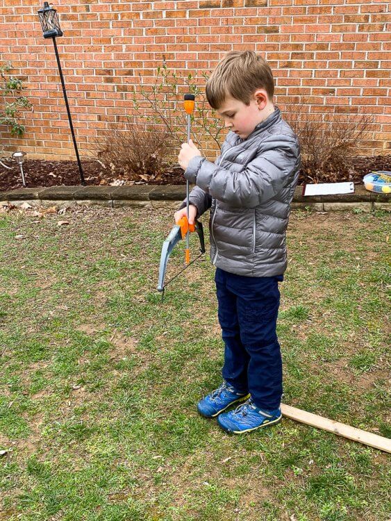 Little boy with a grey jacket getting ready to shoot an arrow.