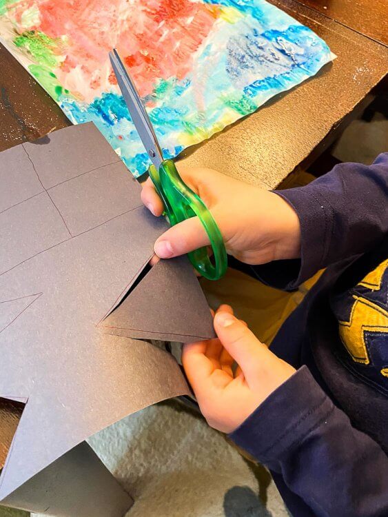 Little boy cutting out shapes in black paper.