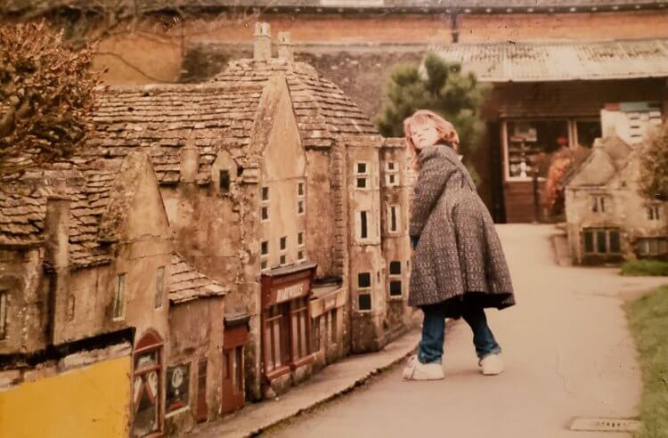 Vintage photo of a little girl standing near a replica village in England.