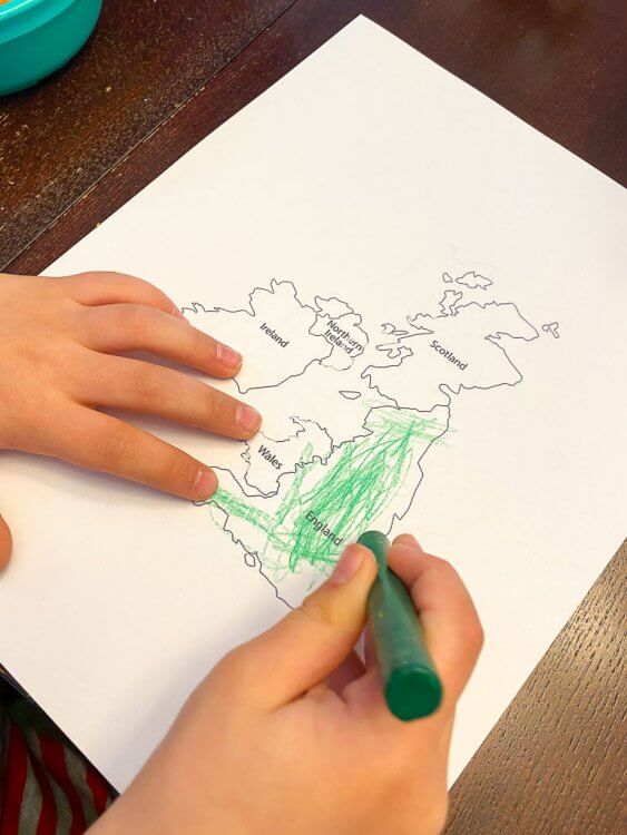 Little boy's hand coloring the map of Great Britain