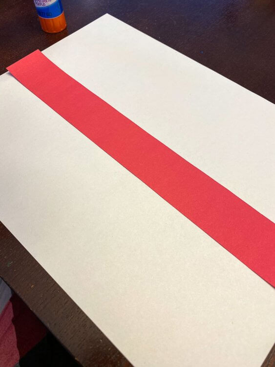Thin red strip of paper laid over a white sheet of paper to make the flag of England