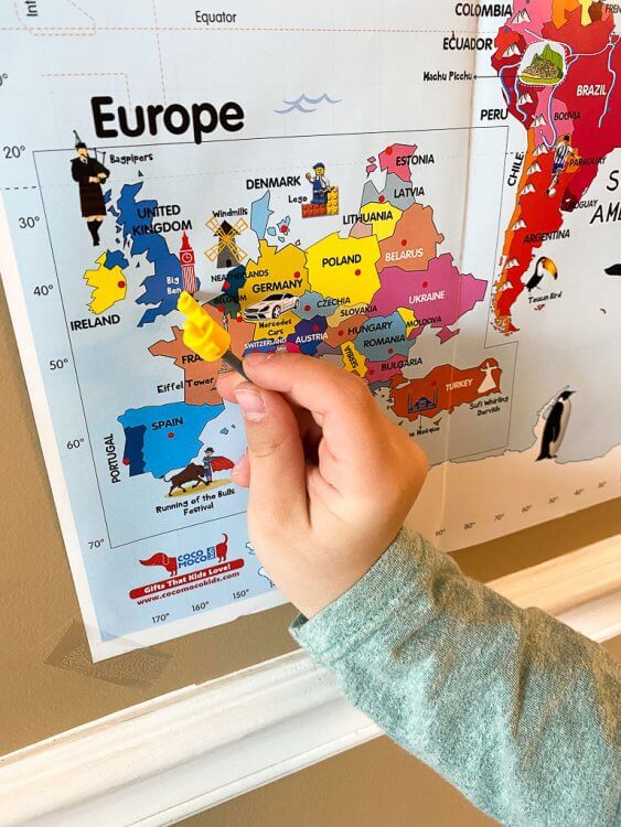 Color world map with a little boy pointing to England.