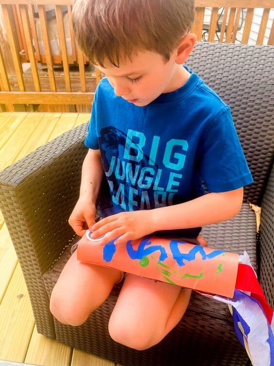 Little boy gluing eyes to his fish kite.