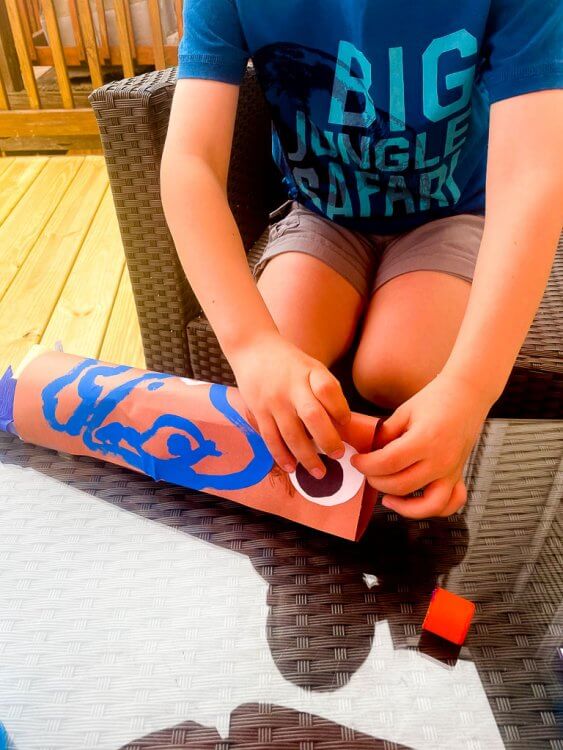 Little boy gluing eyes to his fish kite.