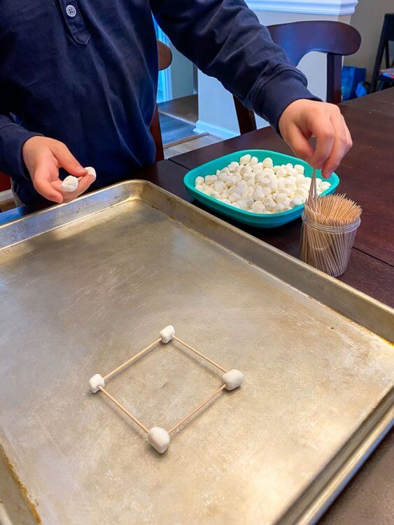 Building with marshmallows and toothpicks on a cookie sheet.