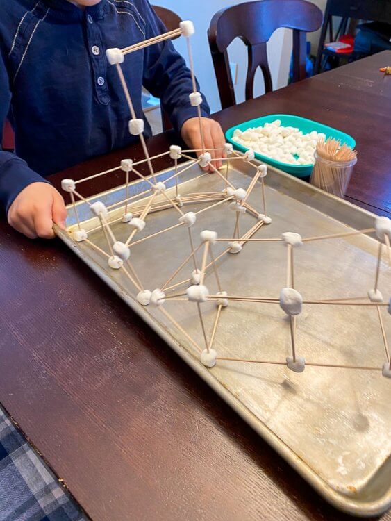Building with marshmallows and toothpicks on a cookie sheet.