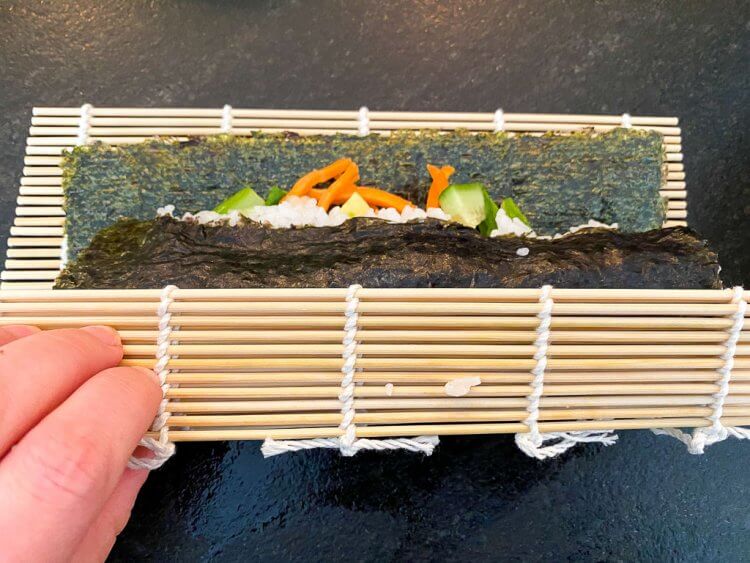 Rolling up the sushi using a bamboo mat.