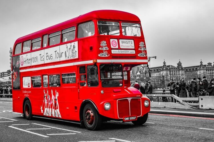Double decker red bus driving on the streets of London.
